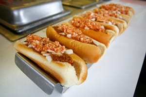A row of hotdogs lined up on a tray